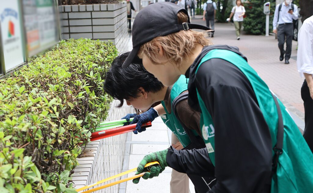 植え込みの中のごみを探す参加者