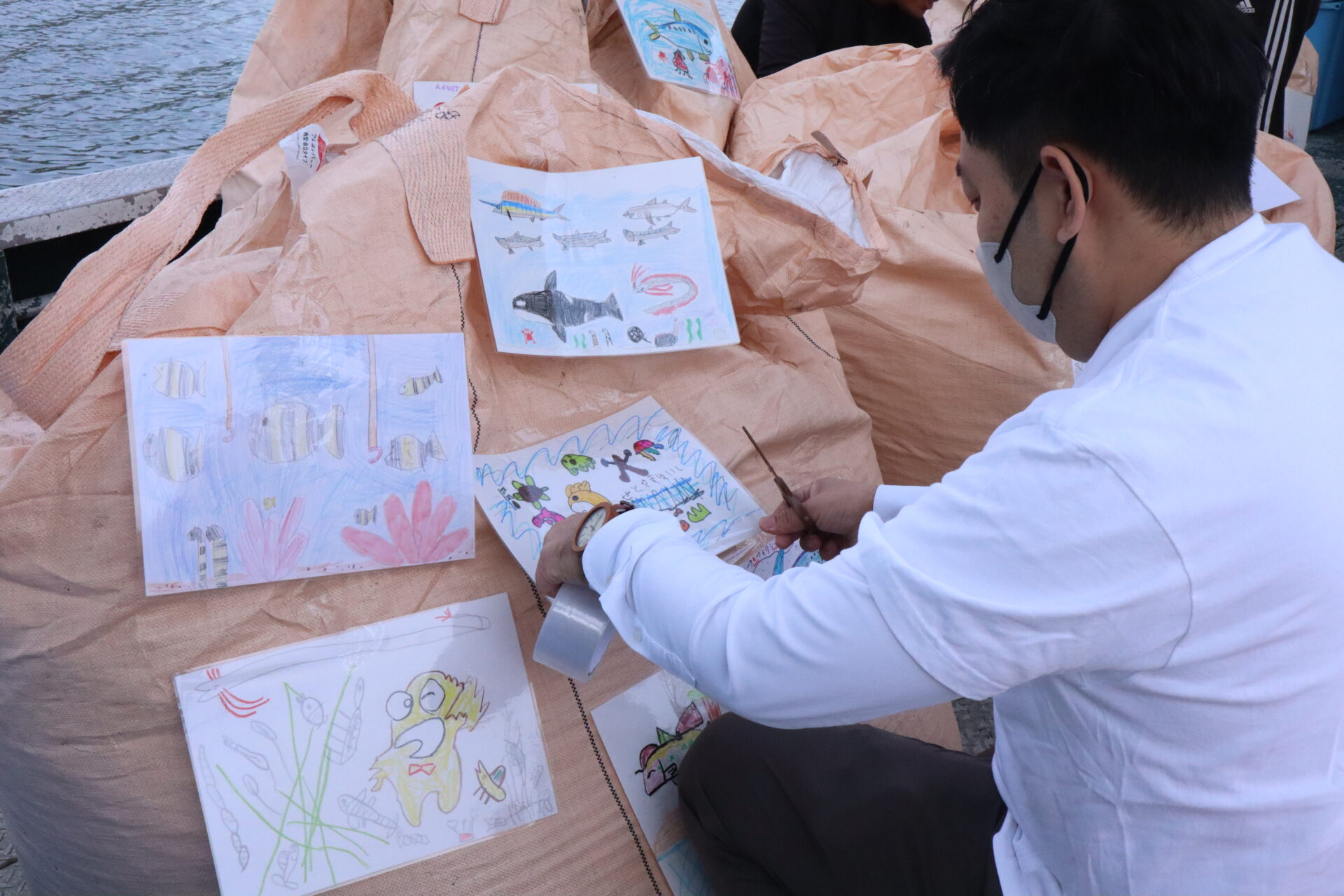 施肥の袋に子供の写真を貼る様子｜エコ調査隊